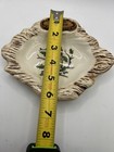Yellow measuring tape along the rim of a ceramic dish with brown owl and green leaf design, made in USA.