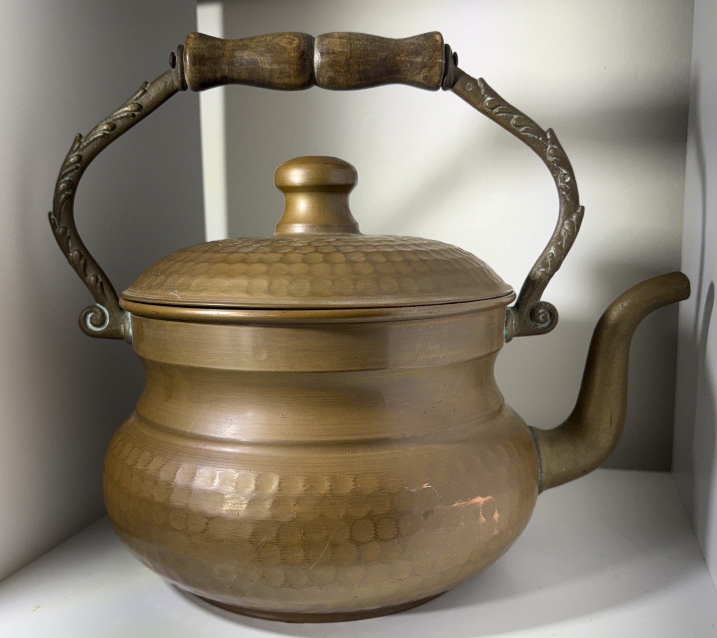 Small hammered copper kettle with wood handle and hammered lid.
