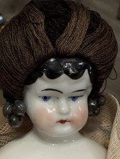 German - 10 porcelain China head doll with wig. Please note torn dress.