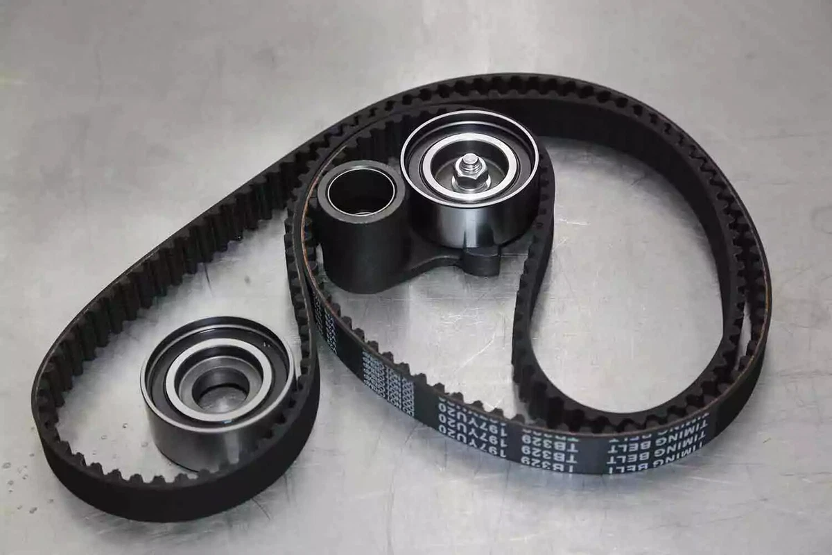 A new timing belt and pulleys displayed on a metal work surface.