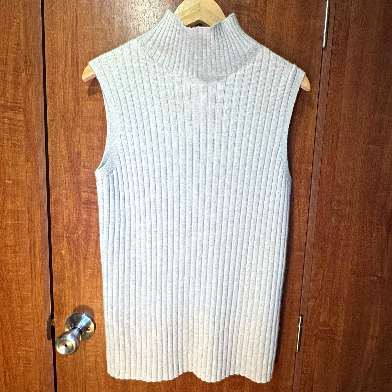 Light gray ribbed cashmere mock-neck sweater vest on a hanger.