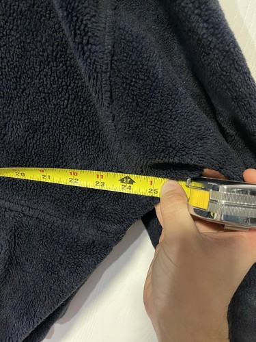 Navy fleece Sherpa hoodie with yellow measuring tape across chest, held in hand against white background.
