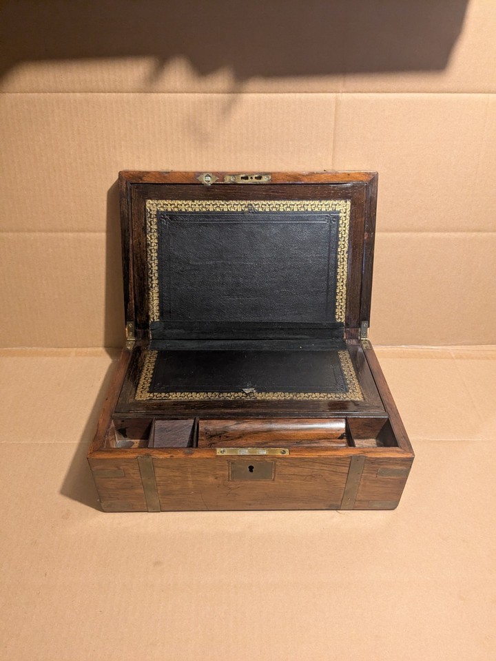 A Victorian-era brass-bound burr walnut writing slope with a hidden secret compartment — functional antique desk art that doubles as a conversation piece and mystery box.
