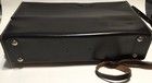 Black leather shoulder bag with white Diamond logo, two silver rivets, and brown leather strap on side.