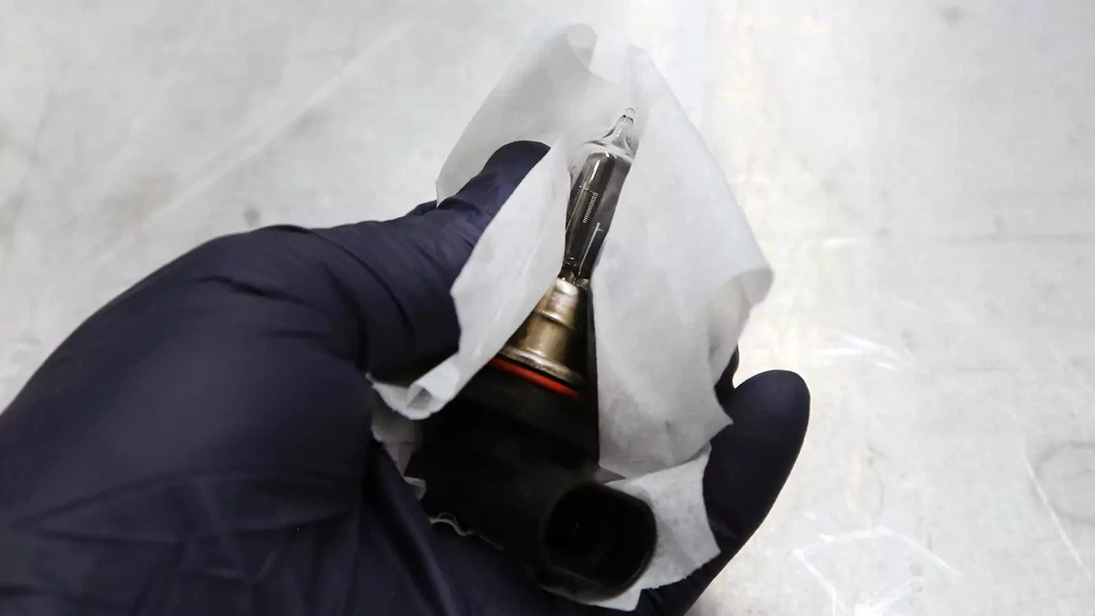 Cleaning a new car headlight bulb.