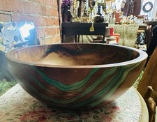 handcrafted wooden bowl with a swirled green and natural wood grain pattern.