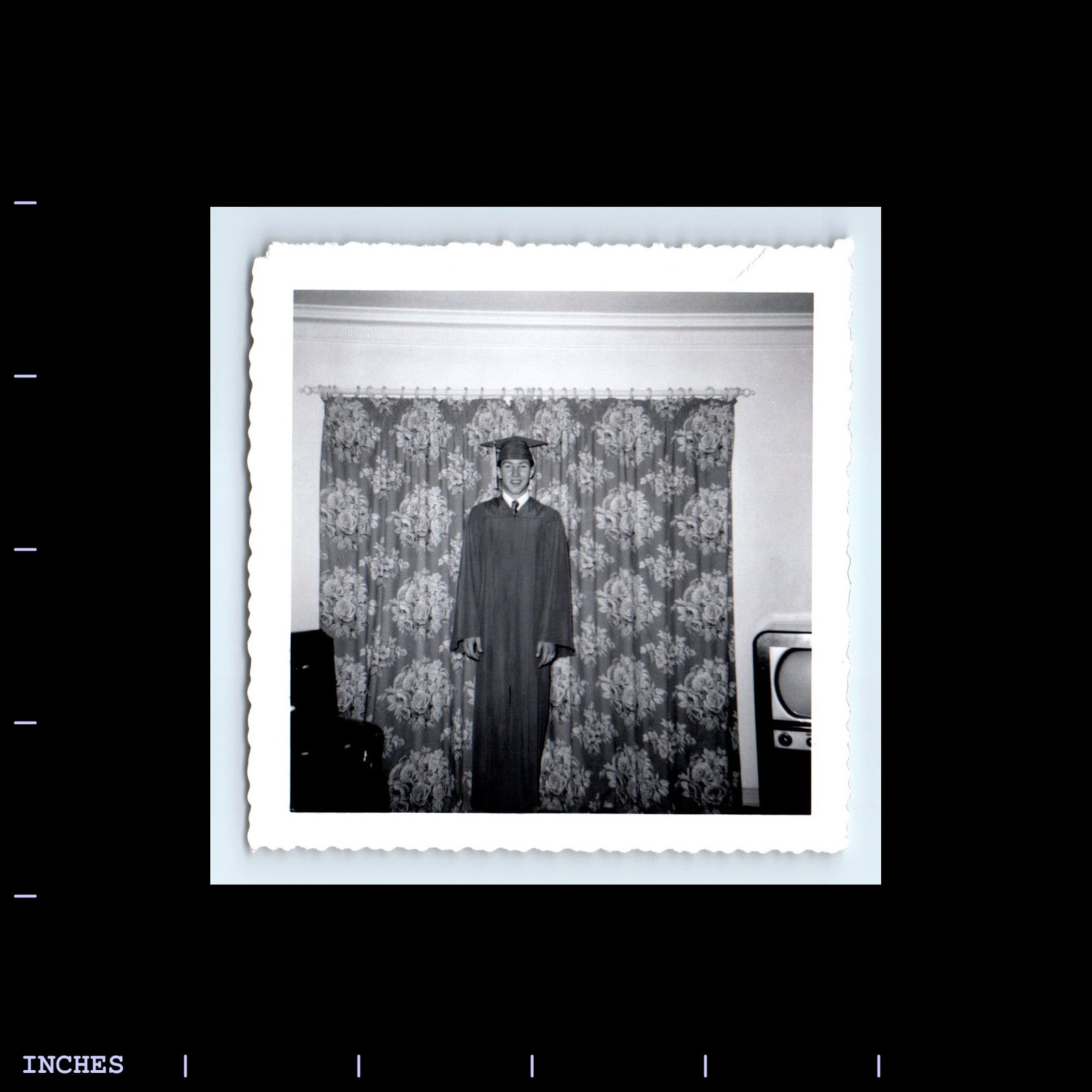 Vintage Black and White Photo of Man in Graduation Cap and Gown Watching Television