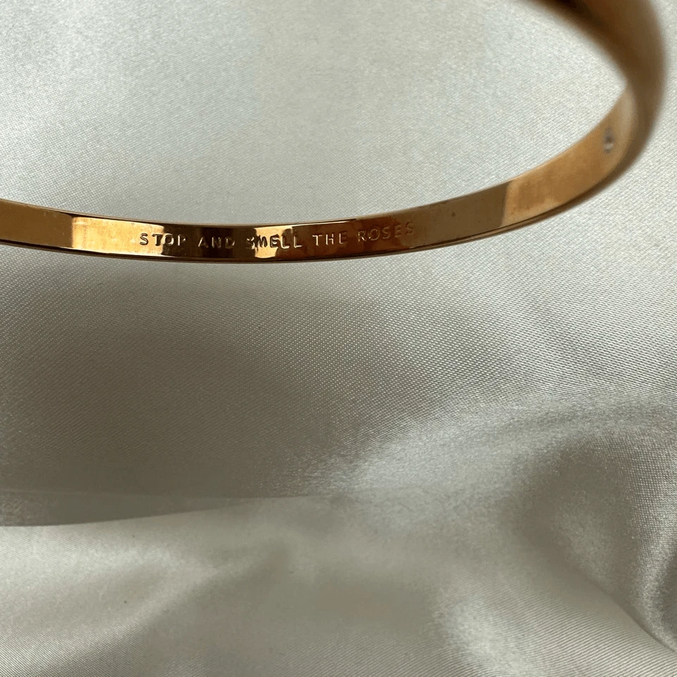 Brazalete Kate Spade bronce delgado apilable. Stop and Smell the Roses” grabado insi Foto 2 de 4
