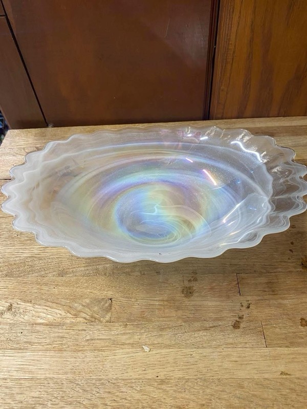 Beautiful iridescent glass bowl has a ruffled edge and swirl pattern.