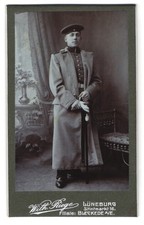 Fotografie Wilh. Riege, L&uuml;neburg, Stintmarkt 16, Soldat in Uniform mit Mantel u