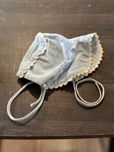 Vintage light blue ribbed baby bonnet with white scalloped trim and ties.