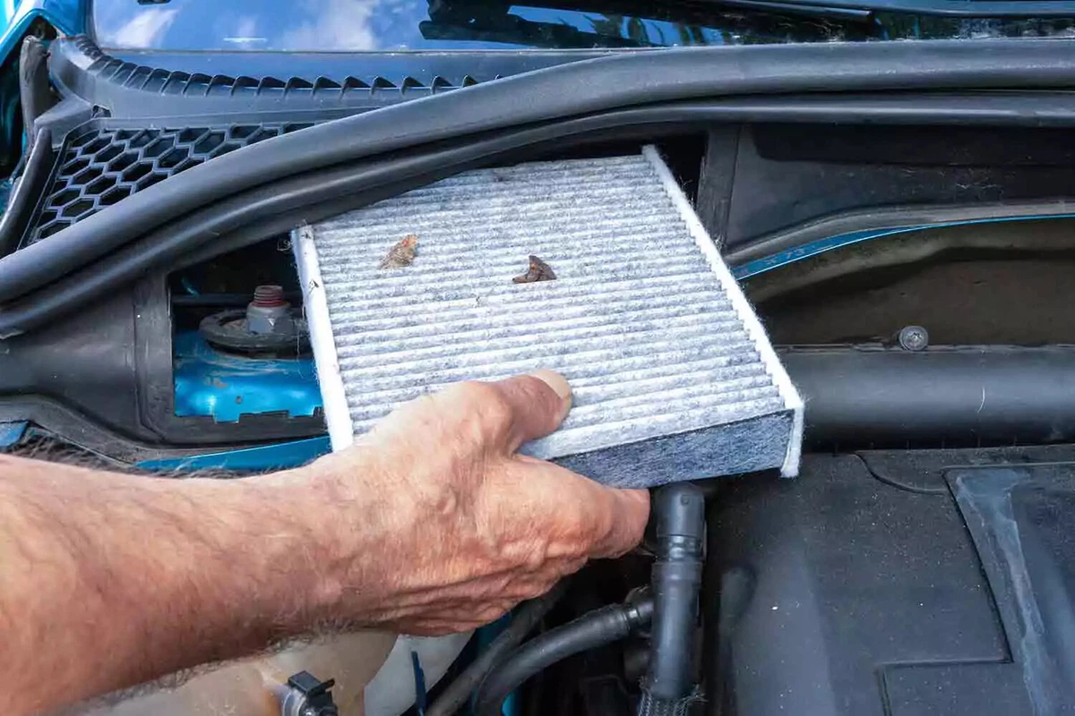 A dirty cabin air filter being removed from a vehicle.