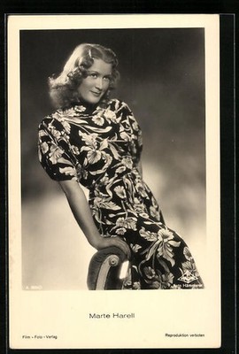 Postcard actress Marte Harell sitting smiling on a chair back 
