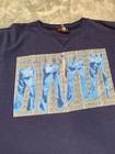 Navy long sleeve Tommy Hilfiger shirt with red, white, and blue denim wave design and repeated “Tommy Hilfiger” text.