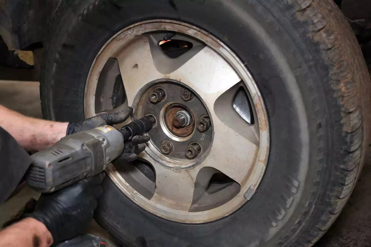 A mechanic uses an impact gun to install the lug nuts.