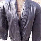 Black leather trench coat with wide shoulder panels, double-breasted buttons, and textured rear seams.