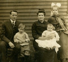 PARENTS WITH CHILDREN POSED IN FRONT OF HOUSE. TONED SILVER PRINT. 