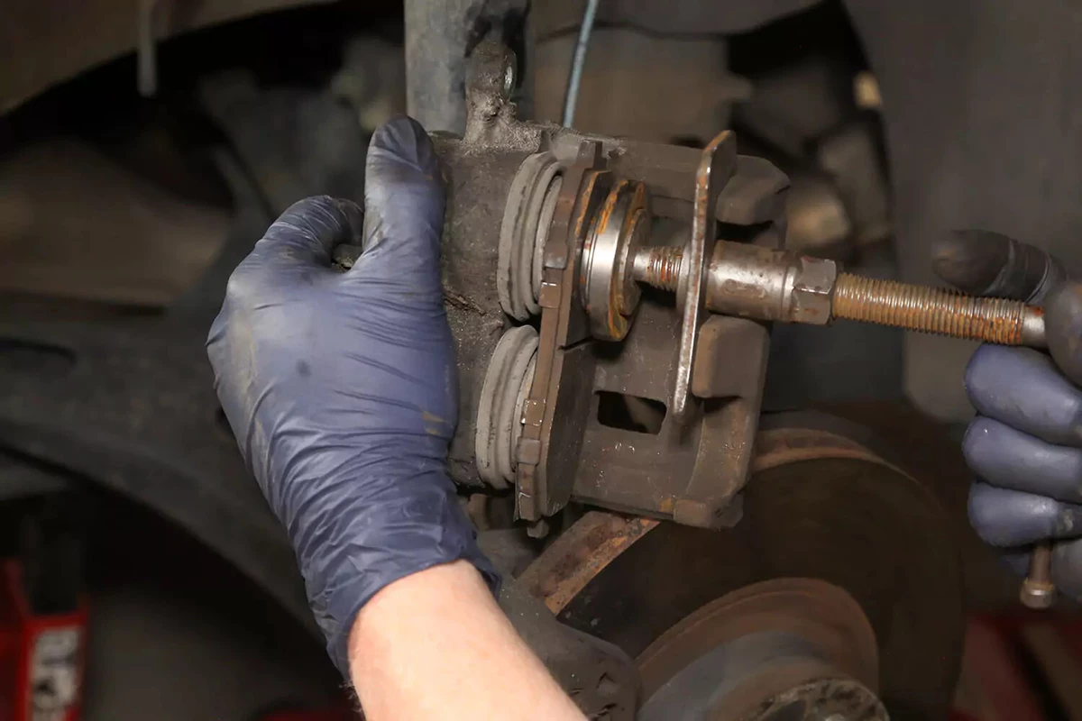 Compressing the brake caliper piston with a brake caliper tool.