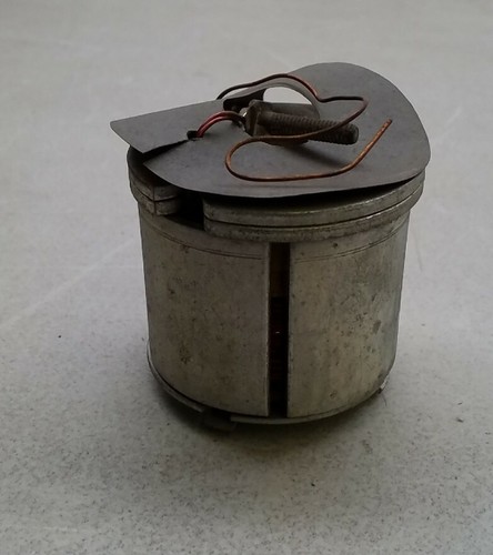 Round silver SW105 Filko ignition parts canister with black lid, exposed metal coil, and visible wiring.