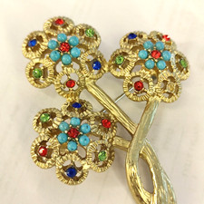 spilla di design a base dorata a tema floreale