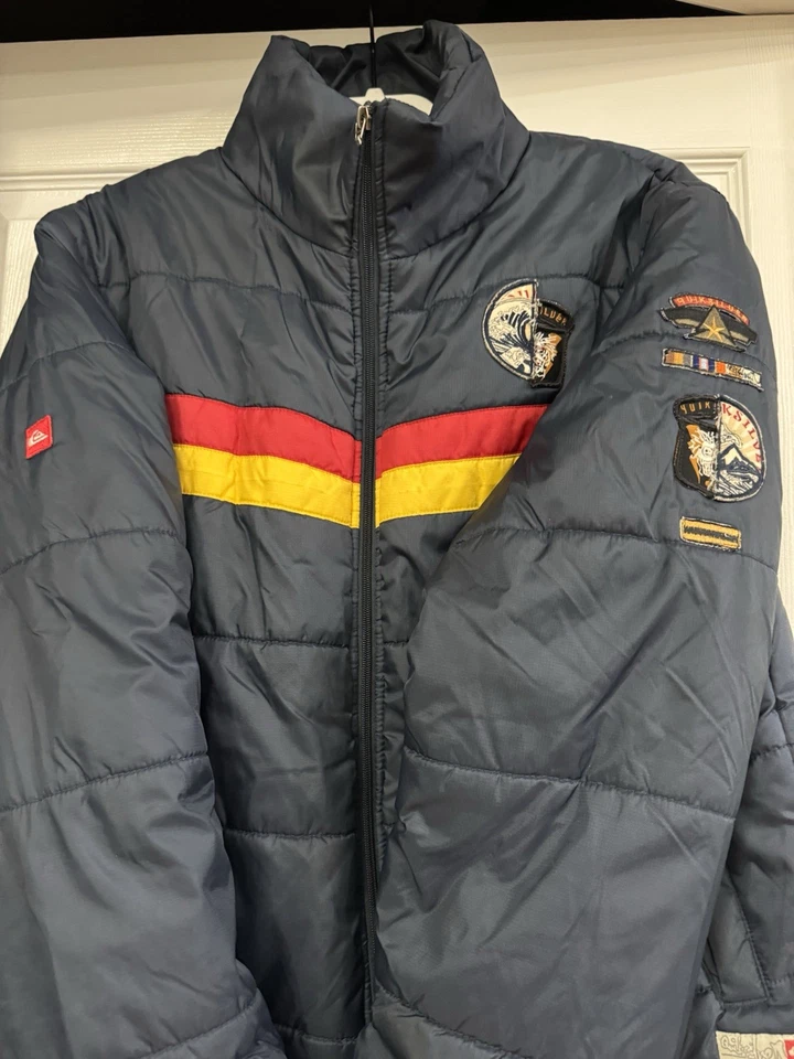 Chaqueta acolchada retro Quicksilver azul marino con rayas rojas y amarillas y logotipo M Foto 4 de 4