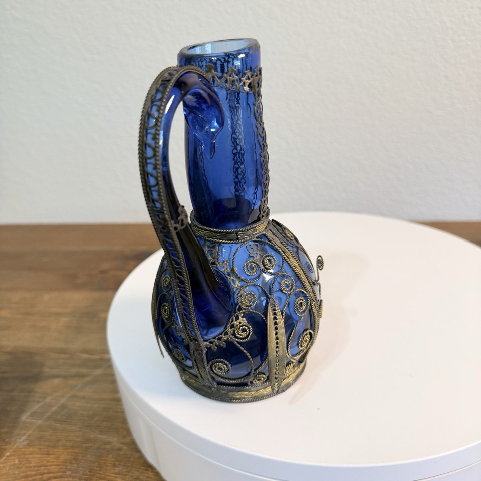 Cobalt blue glass wrapped in ornate metal lattice — the kind of decanter that makes a home bar look like a speakeasy.