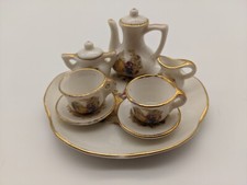 8 piece miniature tea set with two girls on swing, faux gold trim