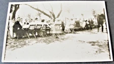 Large group of people sitting in garden outdoors - RPPC-AZO (1918-1930).    