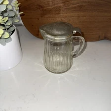 Antique glass syrup Or Molasses pitcher with a metal lid.