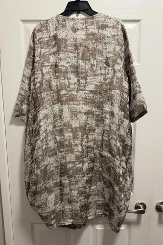 Chalet et Ceci green linen long sleeve dress with back tie waist, displayed on black hanger against white door.