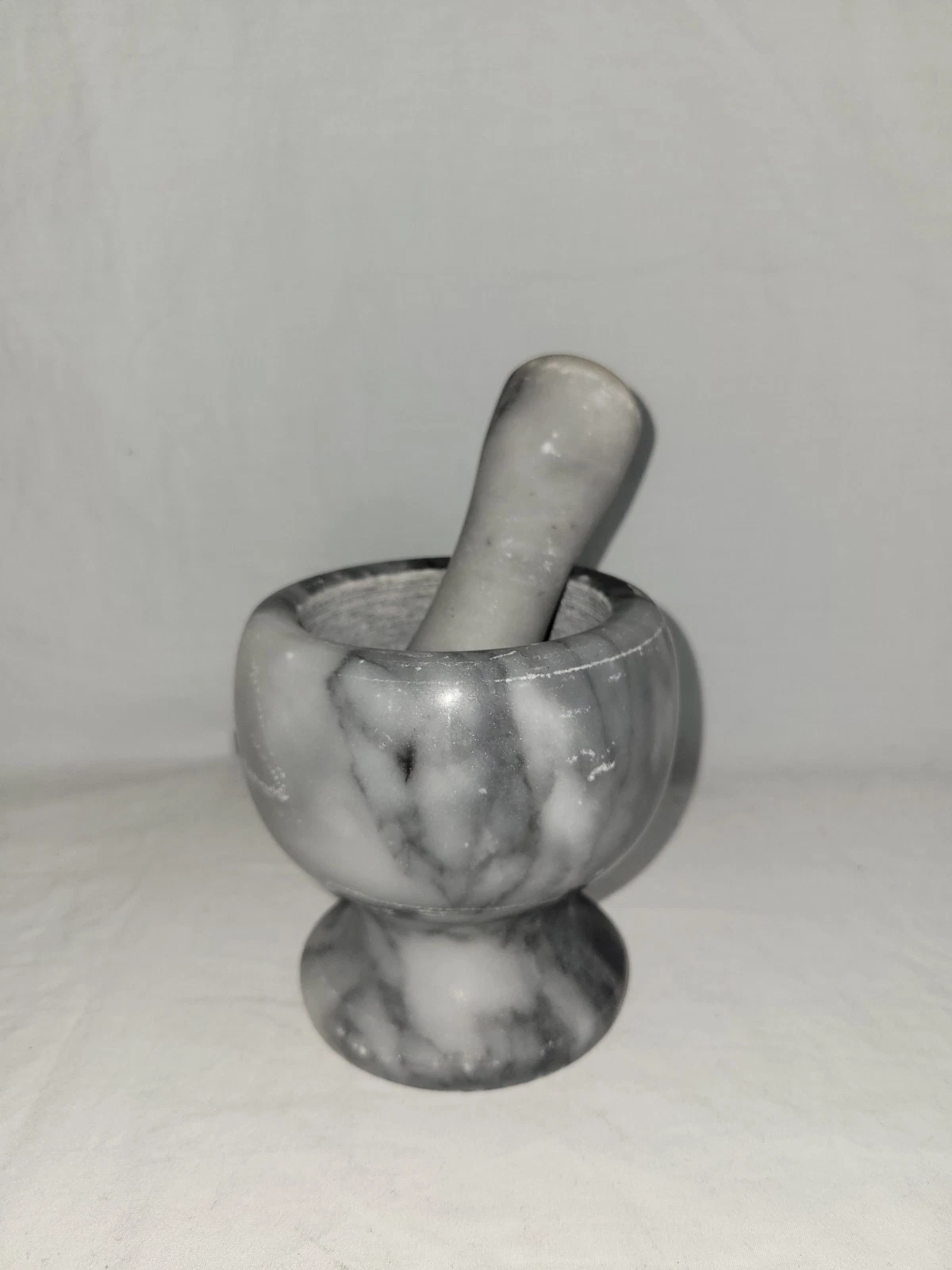 white and gray marble mortar and pestle set, used for grinding herbs, spices,