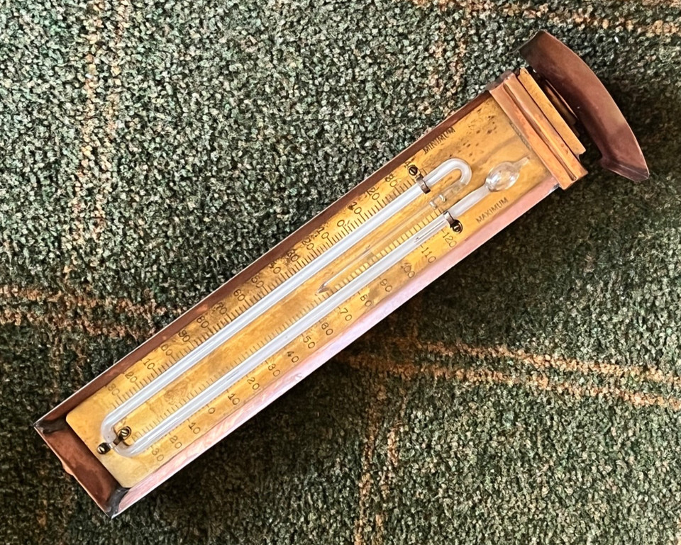 A Victorian-era-style copper & brass max/min thermometer with a twist mechanism — the kind of scientific instrument that looks like it belongs in a gentleman explorer's study.
