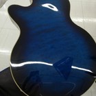 Glossy blue hollow body electric guitar with f-holes, silver hardware, and dark fretboard with white dots.