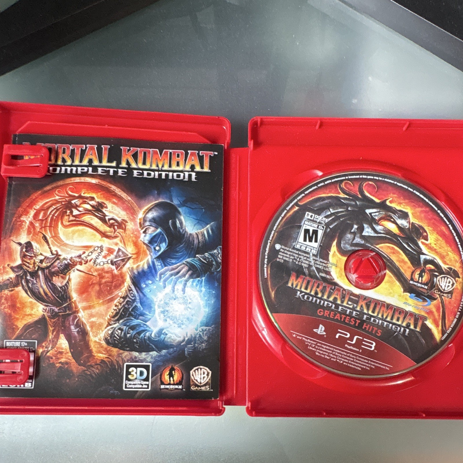 PS3 Mortal Kombat Komplete Edition Greatest Hits case with Scorpion and Sub-Zero in battle, and black game disc labeled with logo.