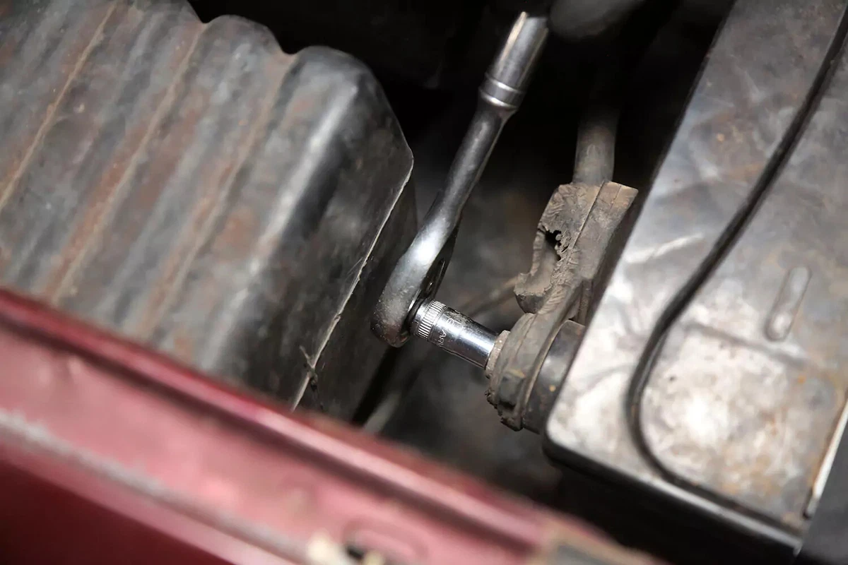 A socket wrench disconnects the negative battery terminal.