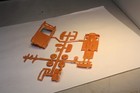 Orange plastic Ferrari and Jaguar XK120 roadster parts made in USA, mint in original box on white surface.