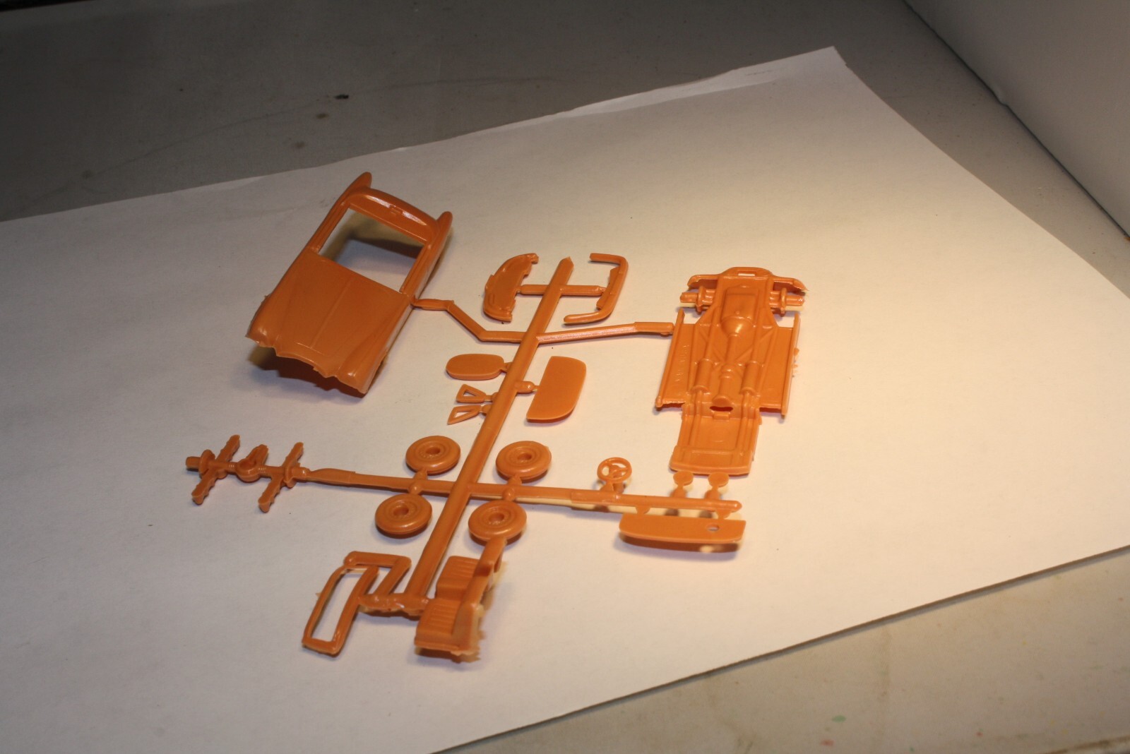 Orange plastic Ferrari and Jaguar XK120 roadster parts made in USA, mint in original box on white surface.