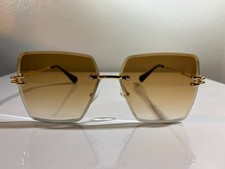 Unisex, rimless, oversized sunglasses with brown lenses and gold wire frame.