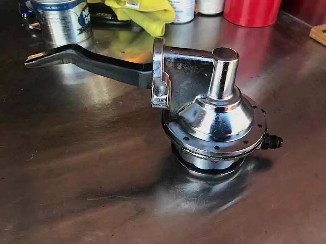 A Holley mechanical fuel pump displayed on a wooden surface.