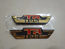 SUZUKI TR125-TRS EMBLEM FRAME SIDE COVER PLASTIC BRAND NEW 1 PAIR