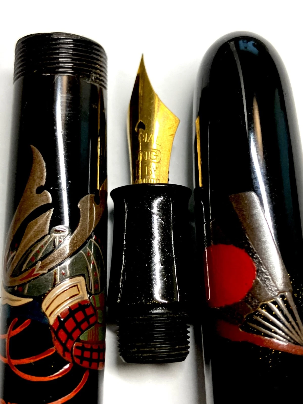 Vintage ink shut off fountain pen with gold tip, black body, red-gold armor design, and detached black ink reservoir.