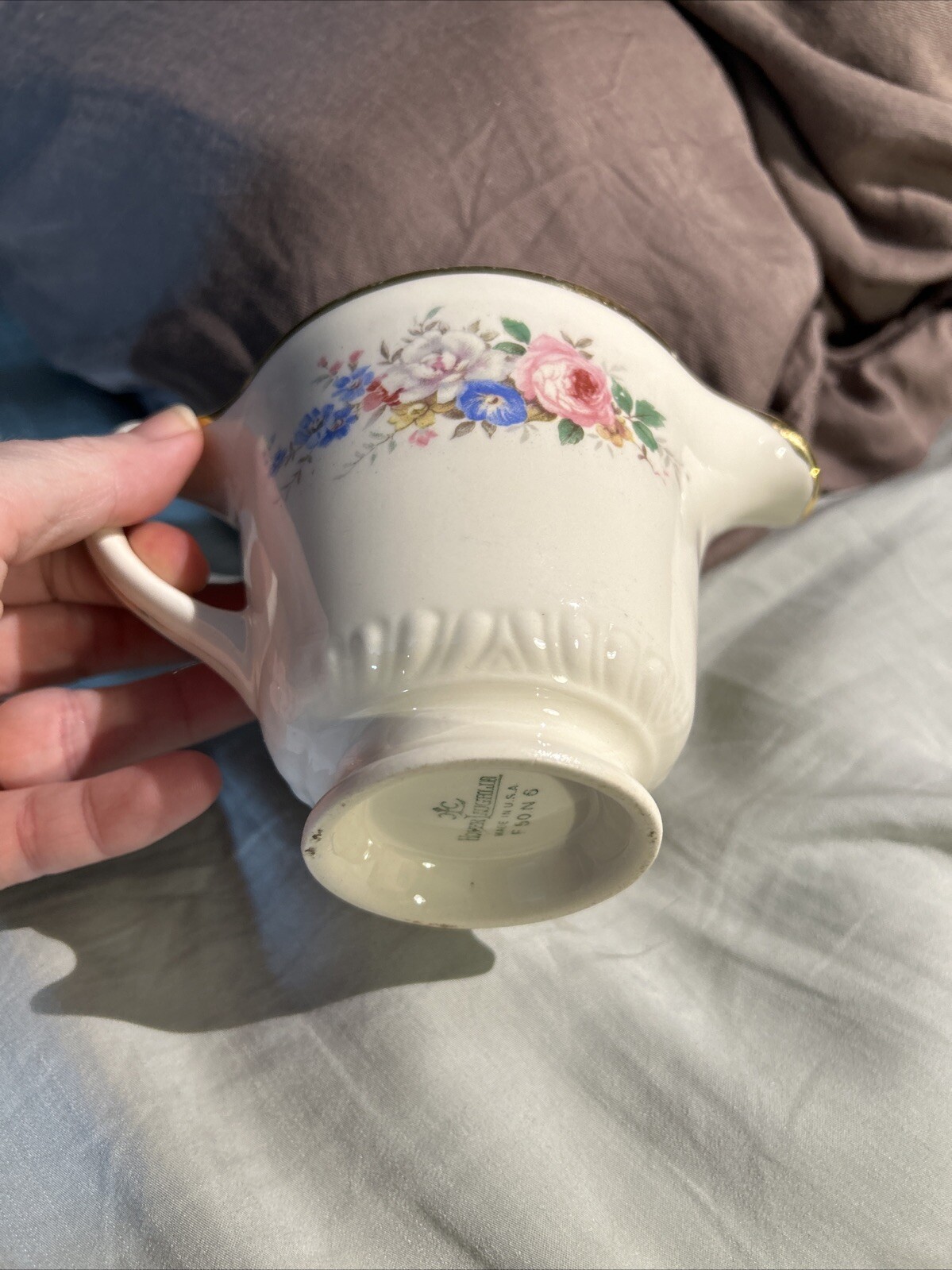 White ceramic mug with gold rim, blue and pink floral print, and embossed “Made in U.S.A.” text on side.
