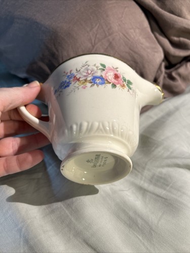 White ceramic mug with gold rim, blue and pink floral print, and embossed “Made in U.S.A.” text on side.