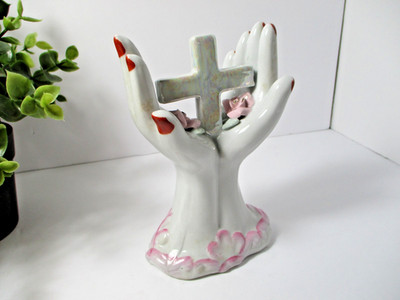 A Ceramic Hand shape figurine Holding a cross and flowers.