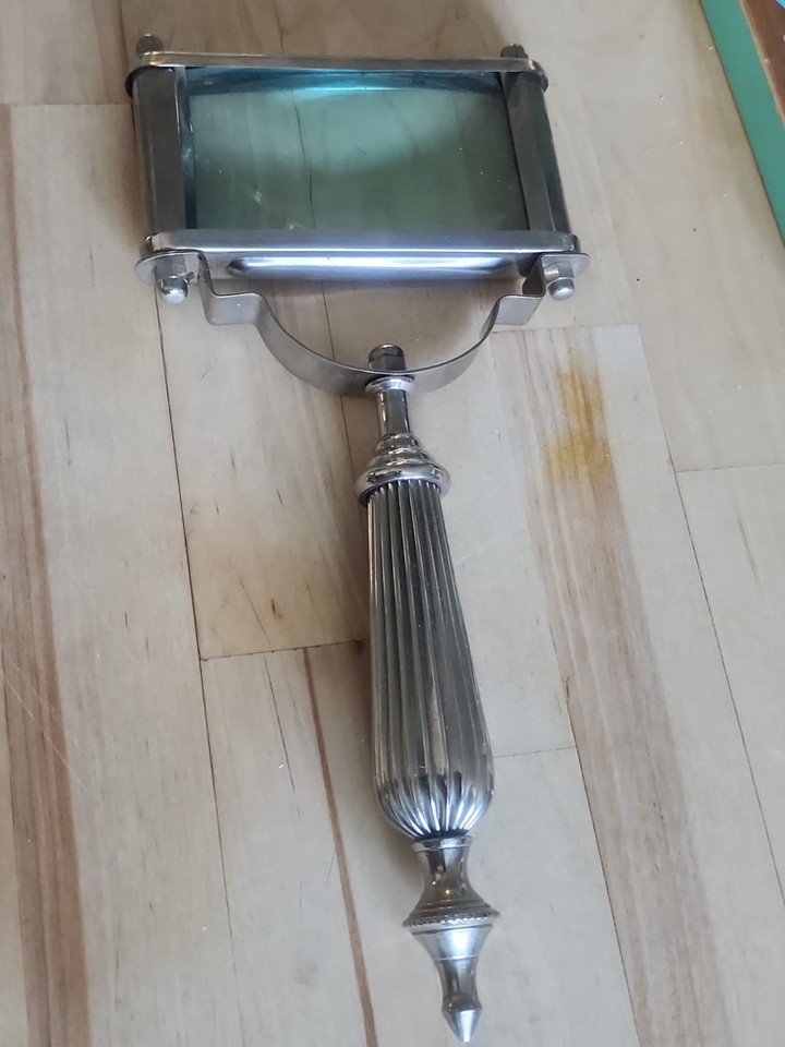 A rectangular antique brass magnifying glass that belongs on a Sherlock Holmes prop table — functional desk decor with serious old-world presence.