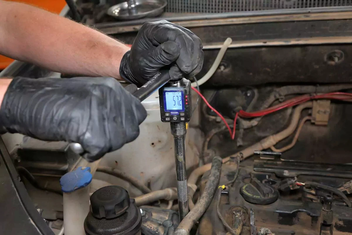 Mechanic using a torque wrench to tighten a motor mount bolt.