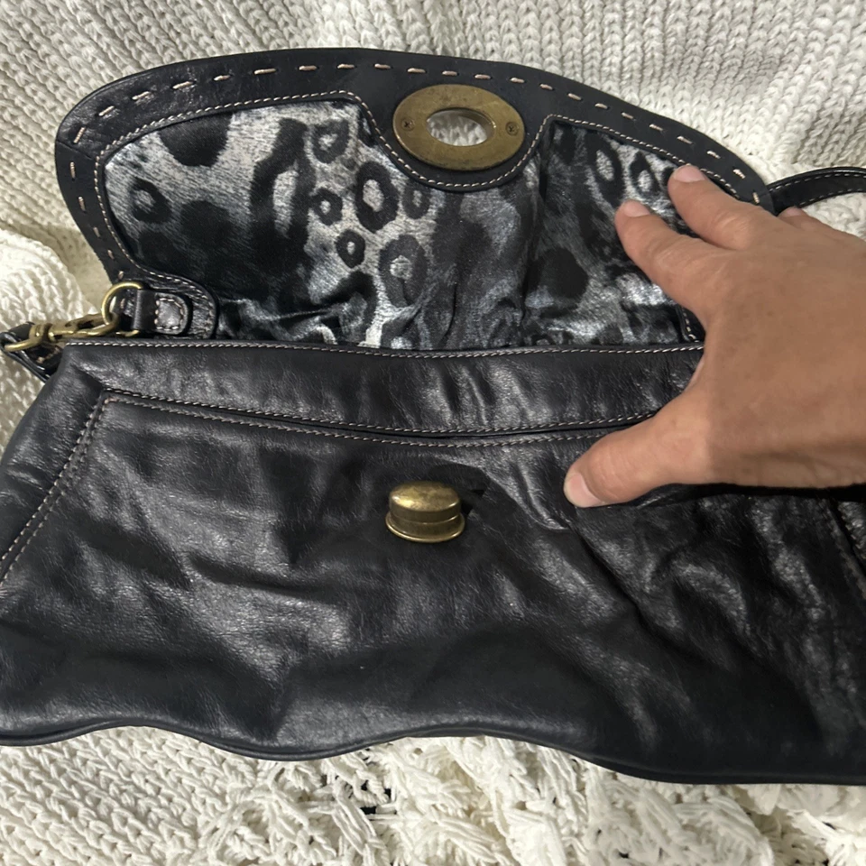 Bolso de mano Kate Landry de cuero negro, tiene una solapa plisada y acanalada con un latón Foto 2 de 4