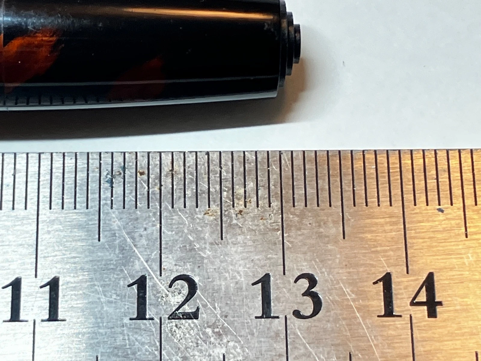 Black vintage fountain pen with gold band beside white ruler marked 11–14 in millimeters.