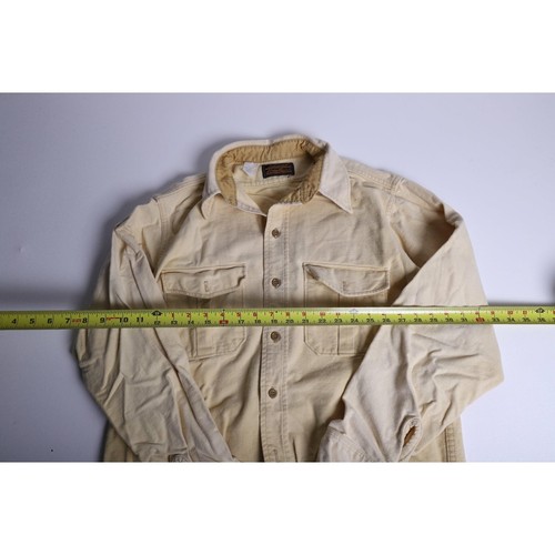 Pale yellow vintage Eddie Bauer men’s L chamois cloth shirt with button front, two chest flap pockets, and made in USA label.