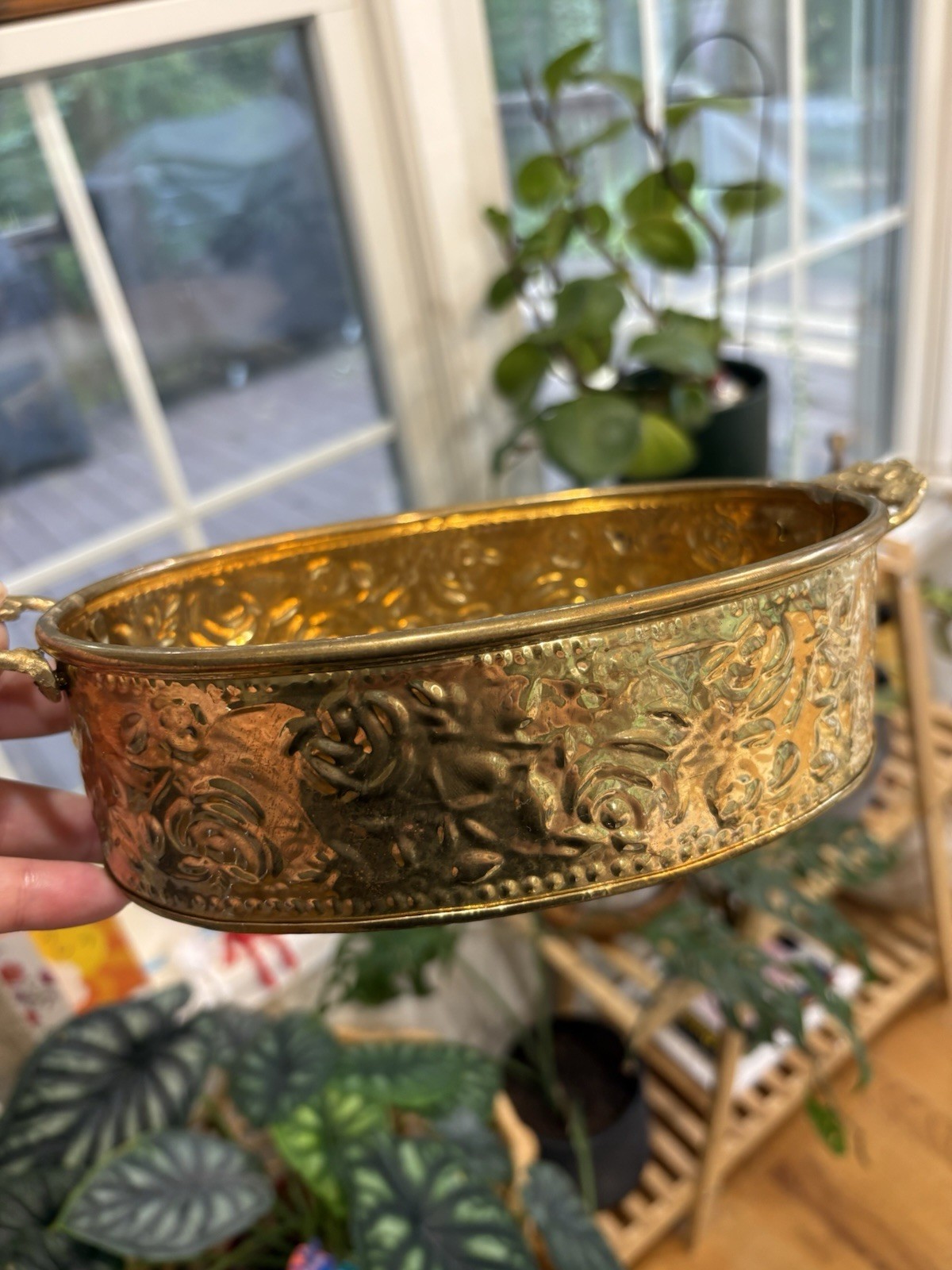 A small oval brass planter with embossed floral detailing and two side handles.